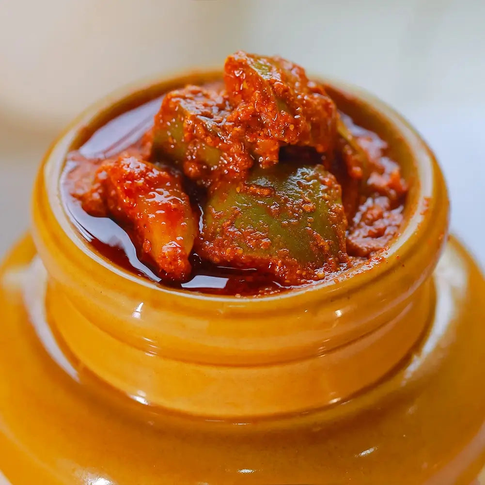 Close up shot of jar of mango pickle on a white background