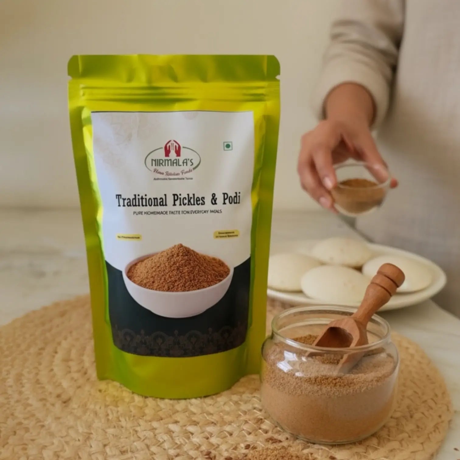 Green package of flax seeds podi with a jar of podi and wooden spoon on a woven mat.