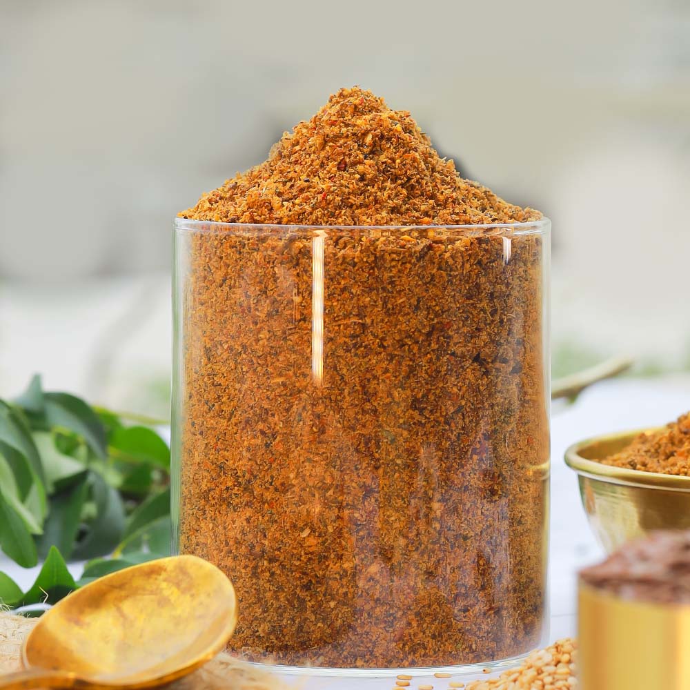 Glass container filled with brown avise ginjala powder on a blurred natural background