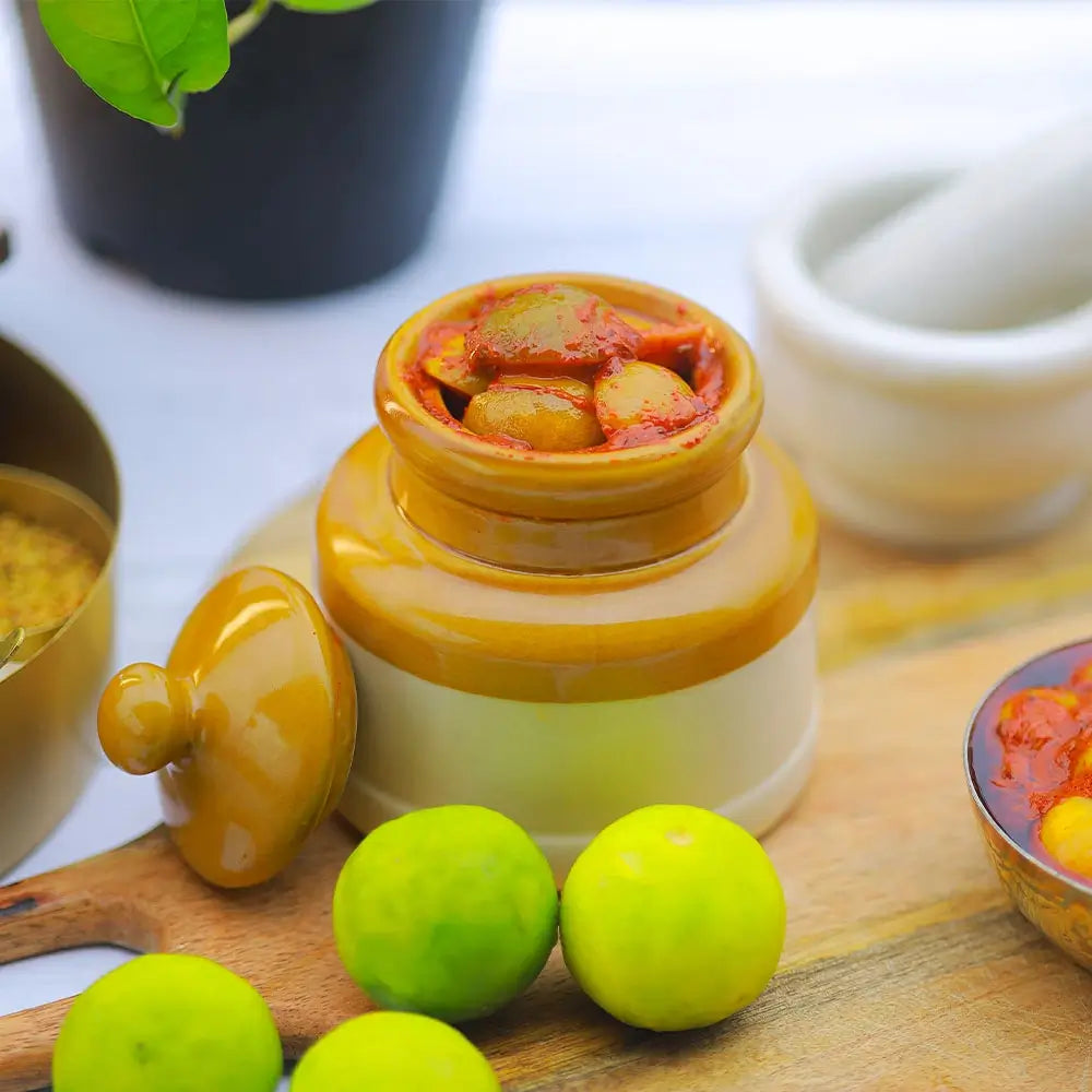 Jar of pickled vegetables on a wooden surface with lemons and a mortar and pestle.