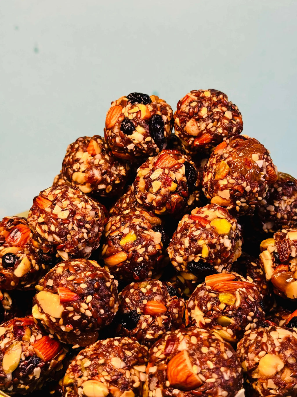 Close up shot of dry fruit laddu with nuts and seeds on a light gray background