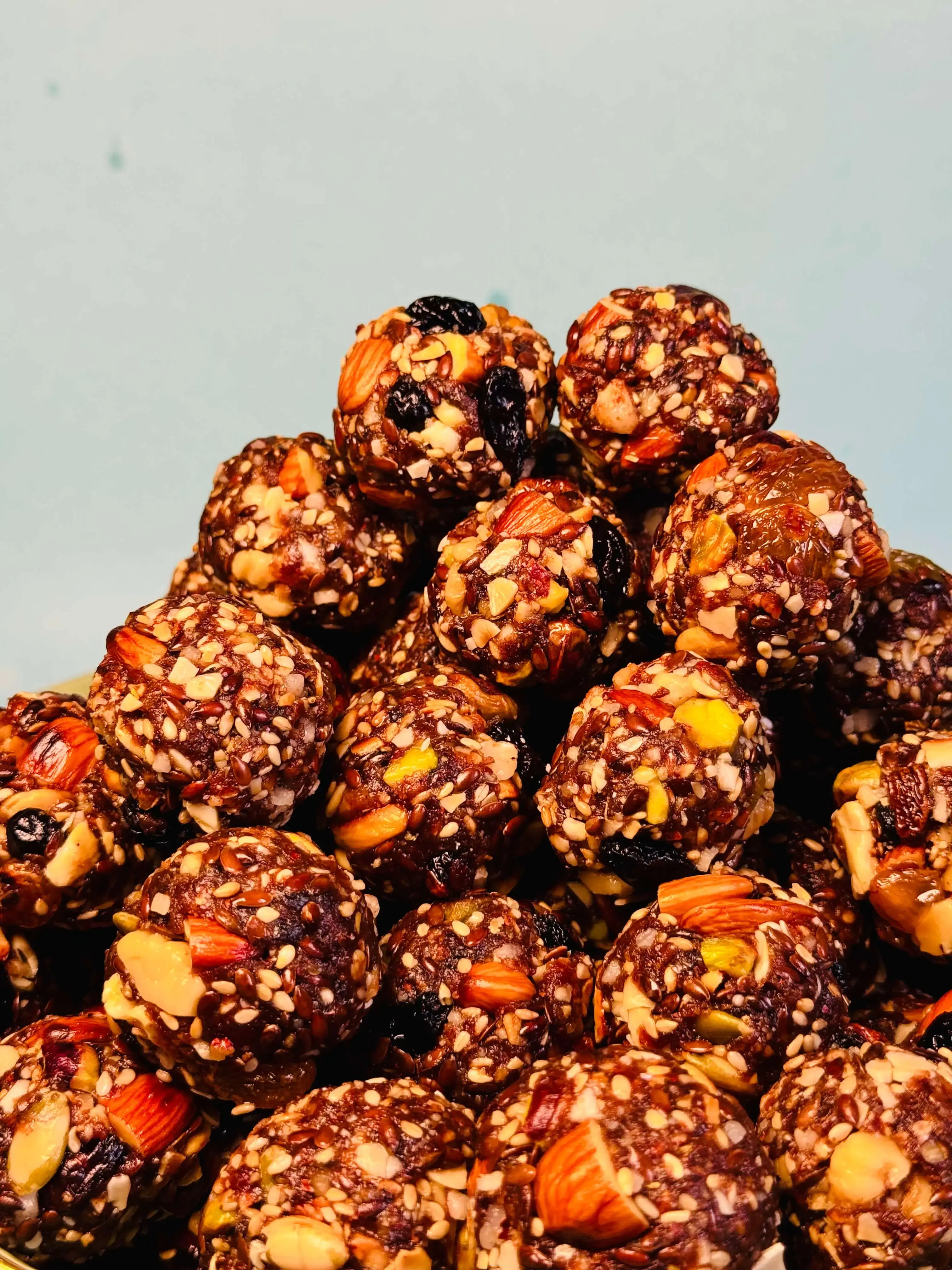 Close up shot of dry fruit laddu with nuts and seeds on a light gray background