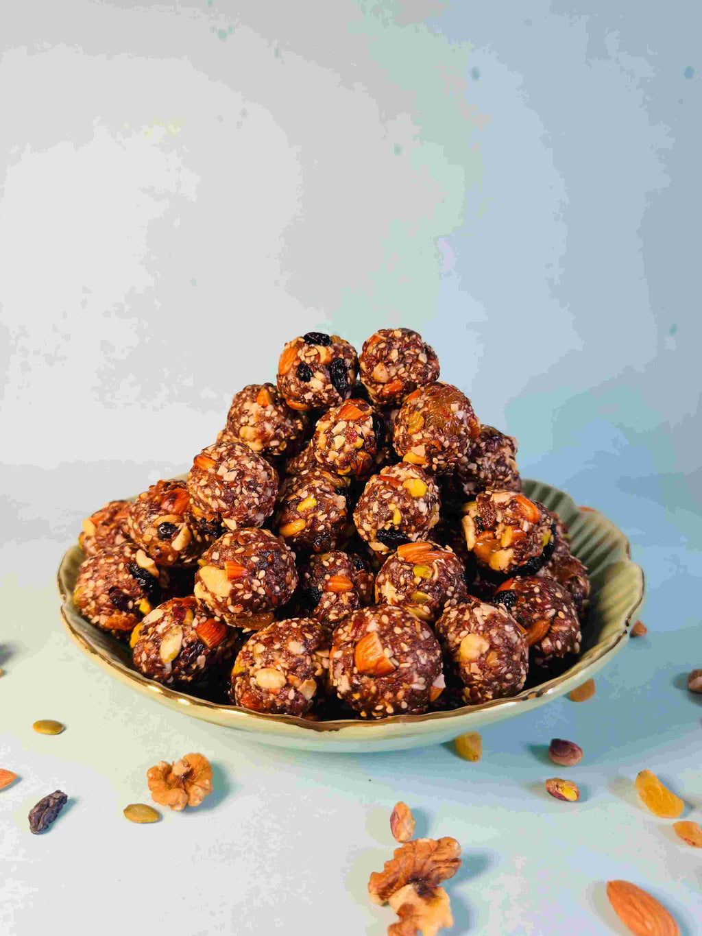 Bowl of dry fruit laddus with nuts on a gradient background