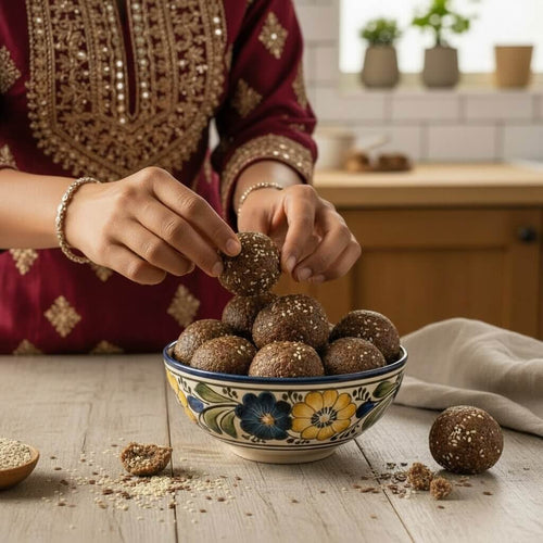 Person handpicking a avisa laddu from a bowl in the kitchen
