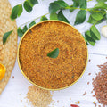 Flax seeds powder in a gold bowl with green leaves on a white background