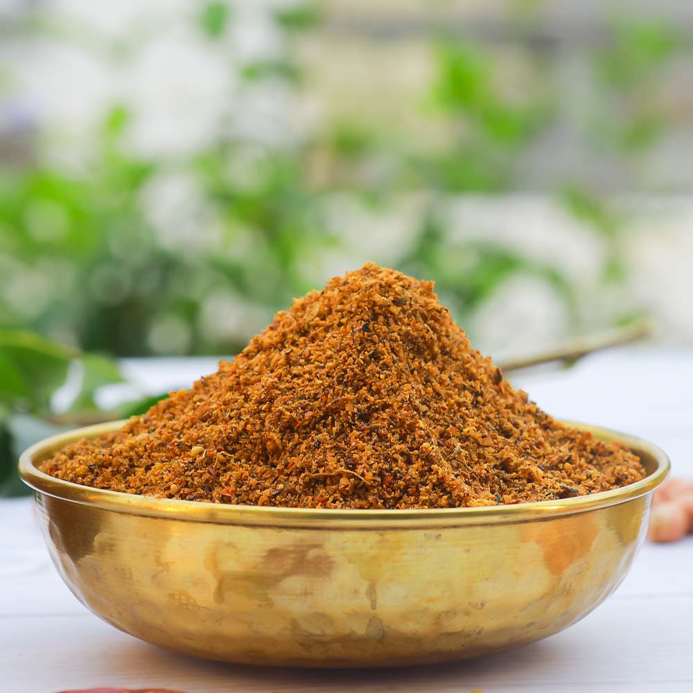 Flax seeds podi in a brass bowl with a blurred natural background