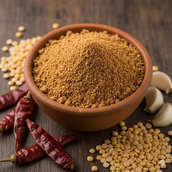 Bowl of kandi karam podi with red chilles and garlic on the table
