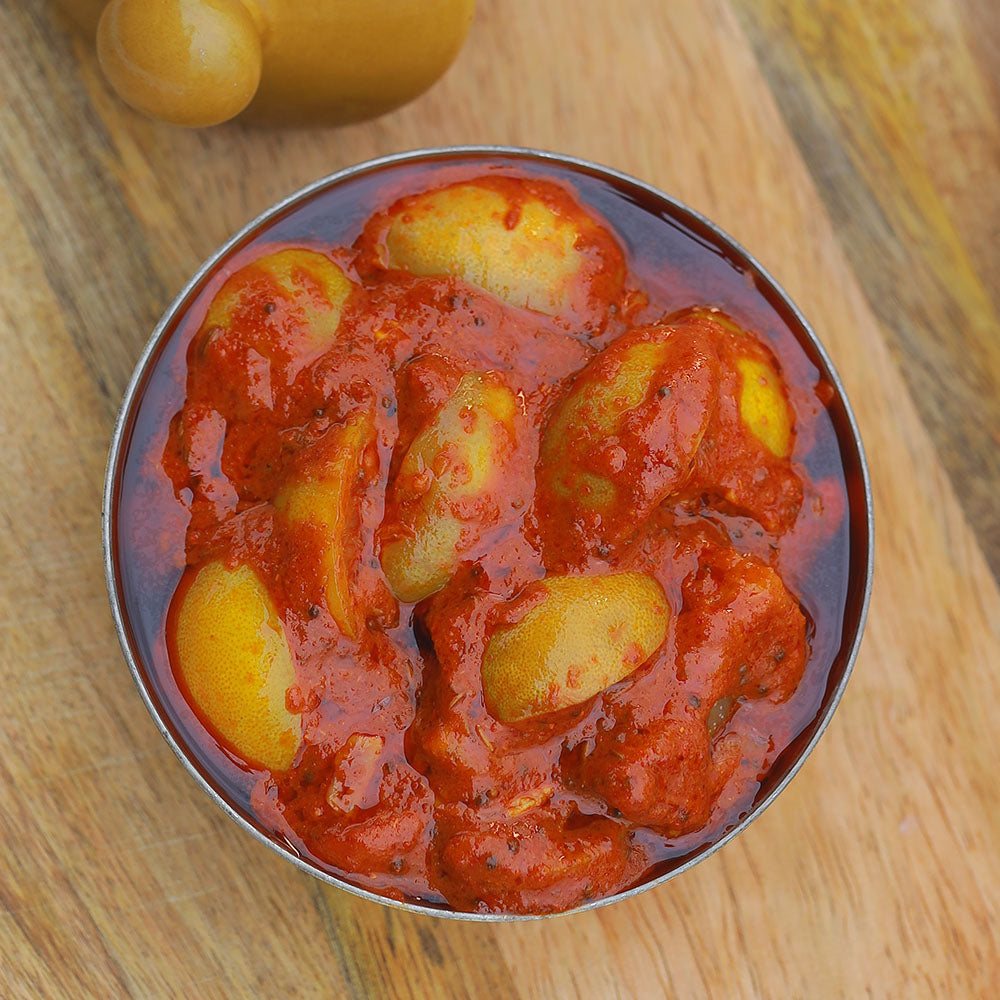 Lemon pickle served in a metal bowl on a wooden surface.