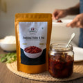 Nirmala's Traditional Pickles & Podi packaging with a jar of mutton pickle on a wooden surface.