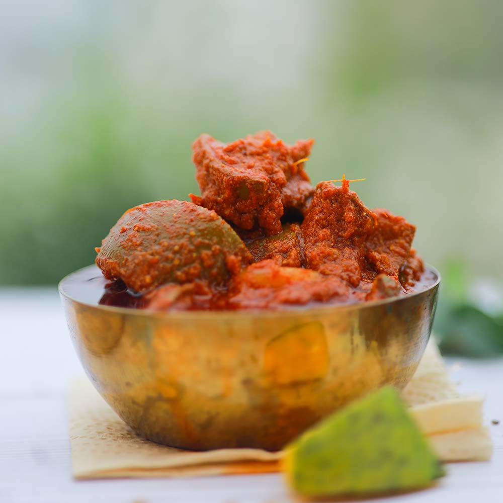 Metallic bowl with red Mango pickle on a light surface