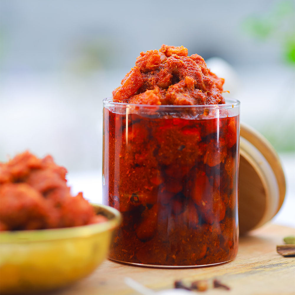 Glass container filled with boneless chicken pickle on a wooden surface