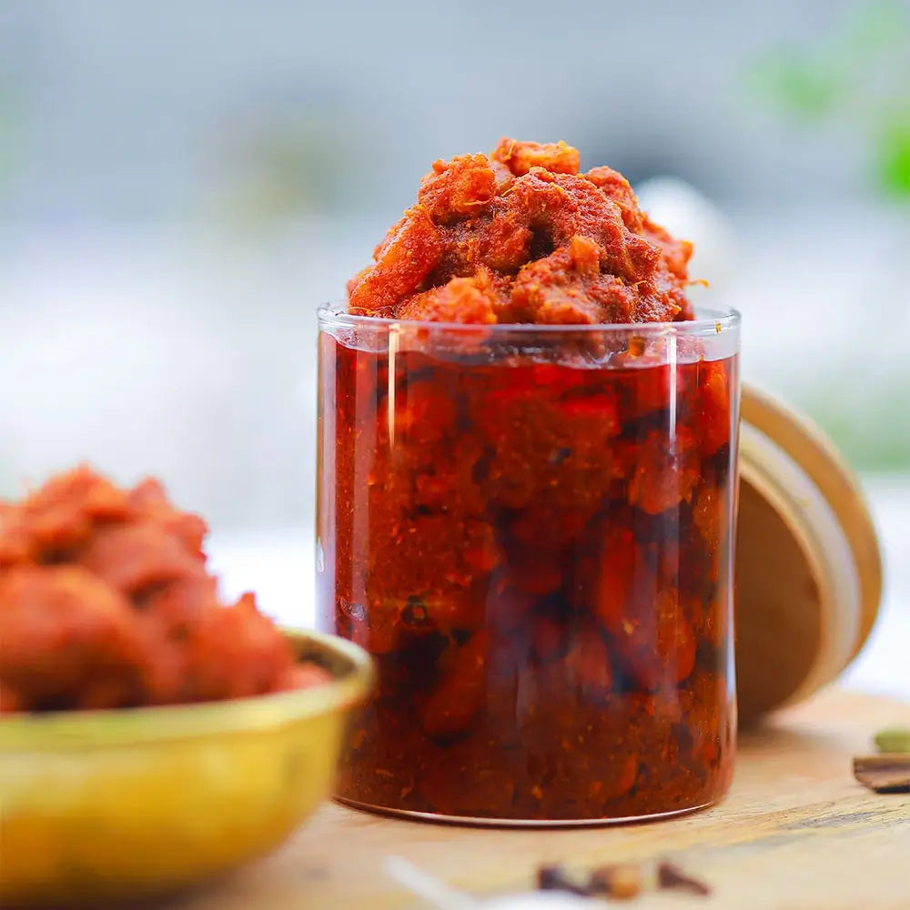 Glass container filled with boneless chicken pickle on a wooden surface